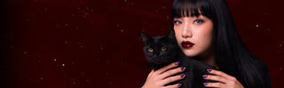 Woman wearing grey colored contacts and metallic purple nails holds a black cat against a starry dark red backdrop.