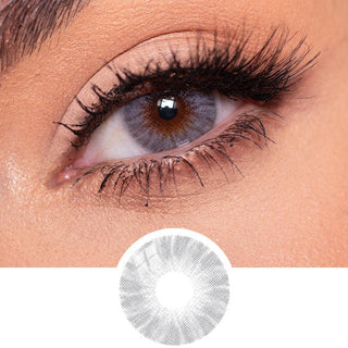Shade Grey contact lens overlaid on a light brown iris, paired with natural eye make up and curled eyelashes on top of the design file of the contact lens itself.