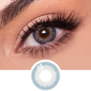 Close-up view of EyeCandys Sugarlook blue contact lens on a model's dark eye, paired with natural eye makeup, above the graphic design of the blue  eye contacts.