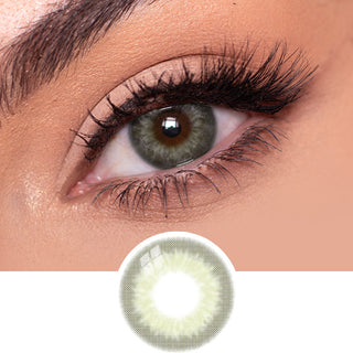 Close-up view of EyeCandys Sugarlook Green contact lens on a model's dark eye, paired with natural eye makeup, above the graphic design of the green eye contacts.