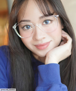 Female model wearing the bright Sunlit Blue circle contact lenses under a pair of clear prescription glasses