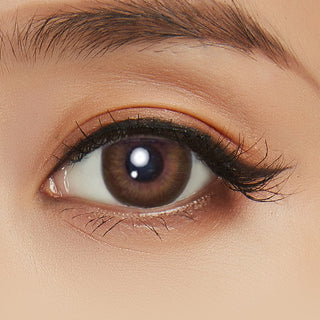 Model's eye wearing the Acuvue Define Radiant Sweet Brown prescription color contact lens with light eye makeup, showing the widening effect of the circle lens on a dark iris.
