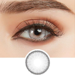 Close up view of EyeCandys Desire Innocent White Grey contact lens over a brown iris, demonstrating color transformation paired with natural eye makeup, next to a cutout of the contact lens