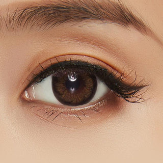Detailed shot of a woman's eye with Pink Label Blossom Brown colored contact lenses adorned with glitter, adding a touch of glamour