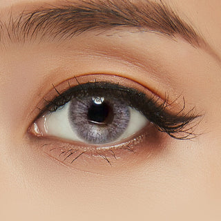 Close-up shot of model's eye adorned with Eyelighter Grey colored contacts for astigmatism, complemented by clean eye makeup, showing the brightening effect of the grey contact lens on dark brown eyes.
