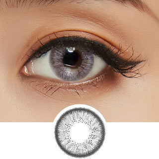 Close-up shot of model's eye adorned with Eyelighter Grey colored contacts for astigmatism, complemented by clean eye makeup, above a cutout of the grey contact lens itself showing the dense starburst pattern.