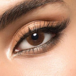 A brown circle contact lens on top of a brown eye with smoky eye makeup and long eyelashes.