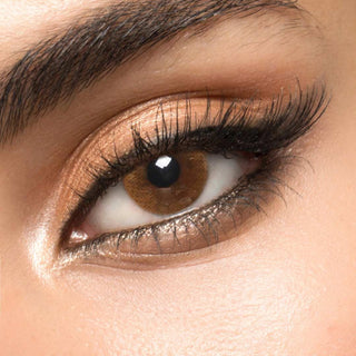 A hazel circle contact lens on top of a brown eye with smoky eye makeup and long eyelashes.