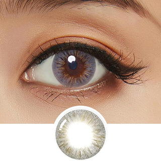 A close-up image showcasing the Birthday Grey contact lens against a white backdrop, worn by a model with dark brown eyes and subtle eye makeup. The picture also includes a cut-out of the contact lens.