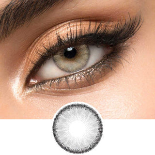 Close-up view of Desire Mist Grey contact lens on a dark brown eye, paired with natural eye makeup, next to a cutout of the contact lens