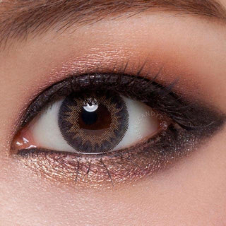 Close-up shot of a model wearing Tri-Color Grey prescription colored contact lens in one eye that is naturally dark-brown