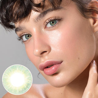 Close-up photo displaying the vibrant green hue of the Libre Green contact lens on a white background, modeled by someone with dark brown eyes and natural eye makeup. The image also includes a close-up of the contact lens.