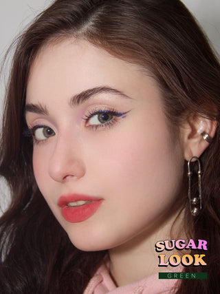 Dark-eyed model showcasing EyeCandys Sugarlook Green colored eye lenses with complementary pink lipstick